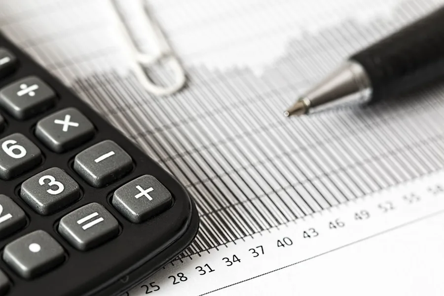 Calculadora e caneta sobre um gráfico financeiro